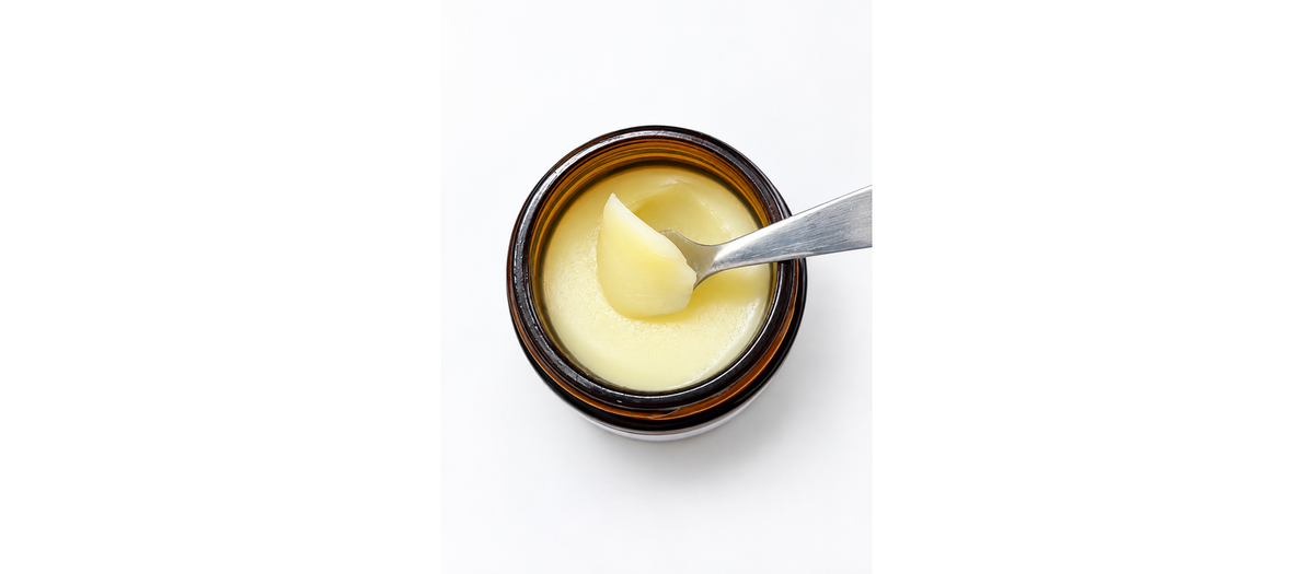 An open jar of Willow & Watch Intensive Tallow Balm with a spatula lifting out the balm